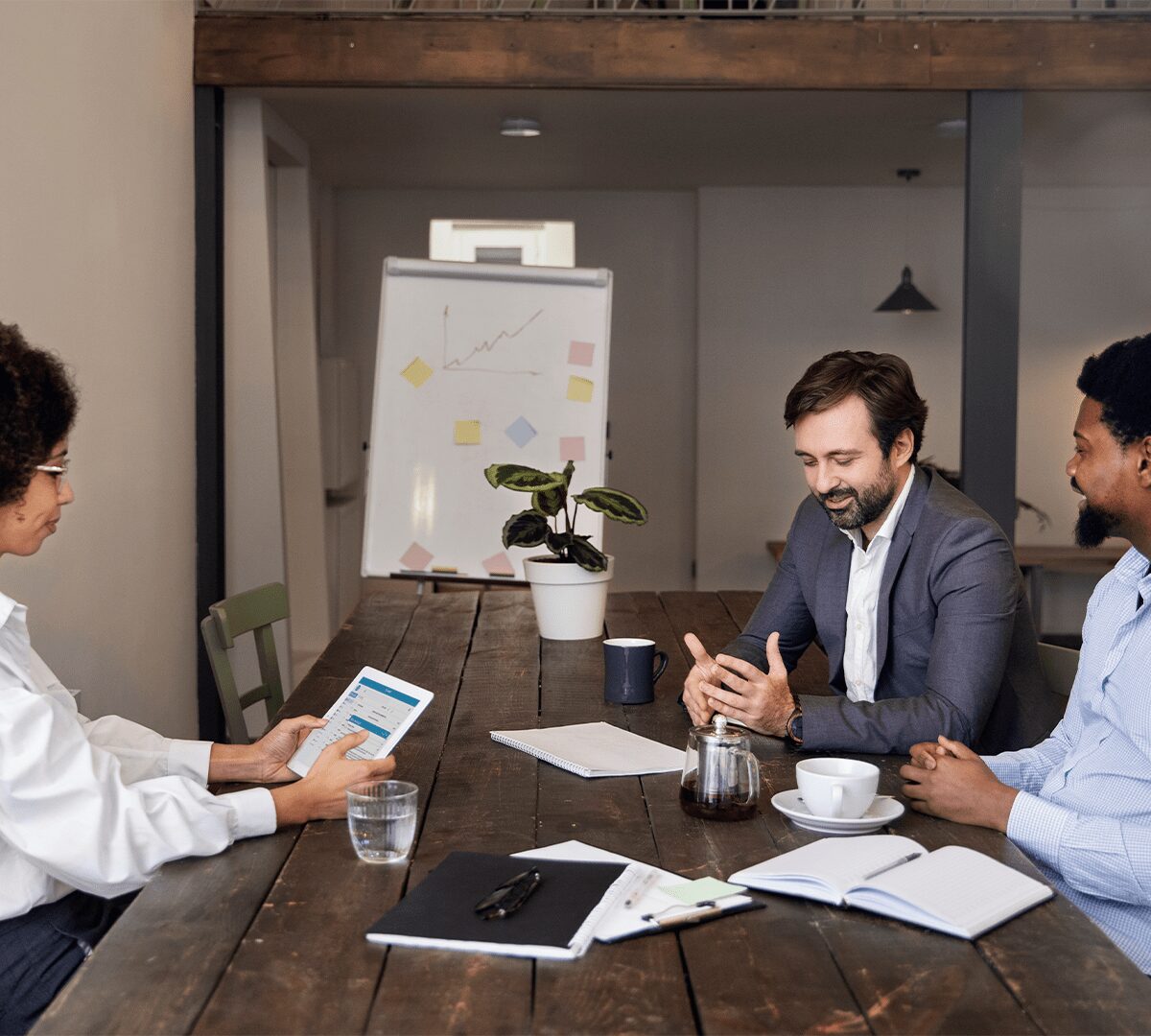 Three business professionals engaged in discussion at a table, representing an engineering consultancy firm.