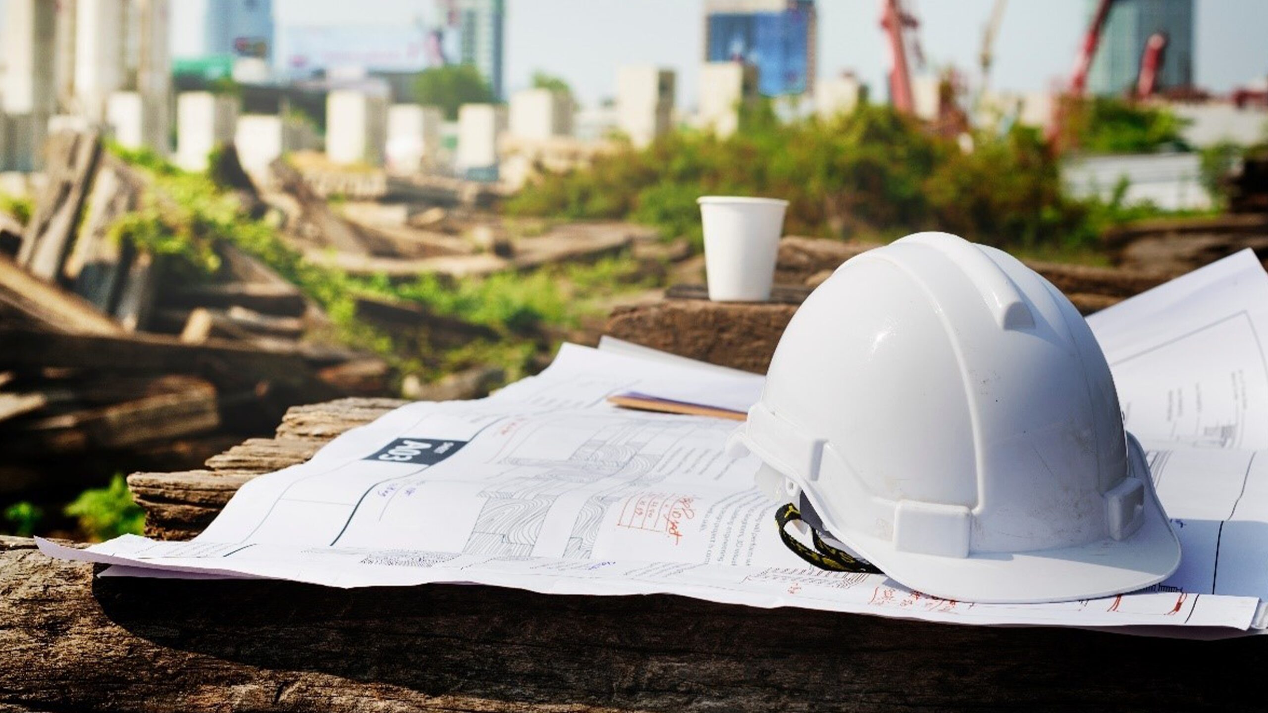 Image featuring a construction hat and construction plans are arranged, highlighting the focus of construction management businesses.