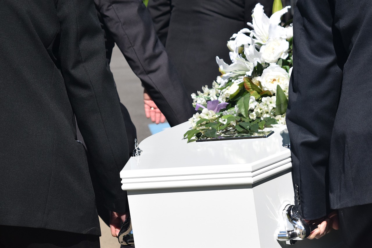 A solemn funeral procession featuring a casket, led by mourners in respectful attire, reflecting a moment of remembrance.