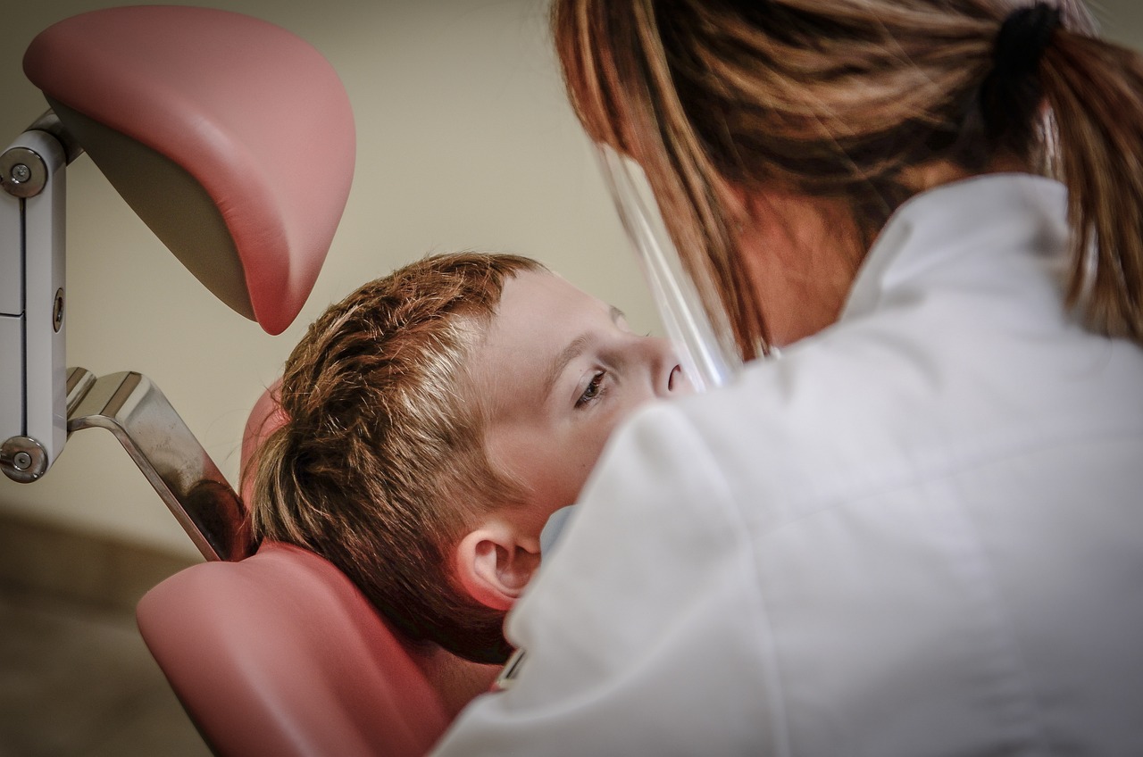 A dental assistant agency owner, sits in a chair with a child, showcasing a moment of care and connection.