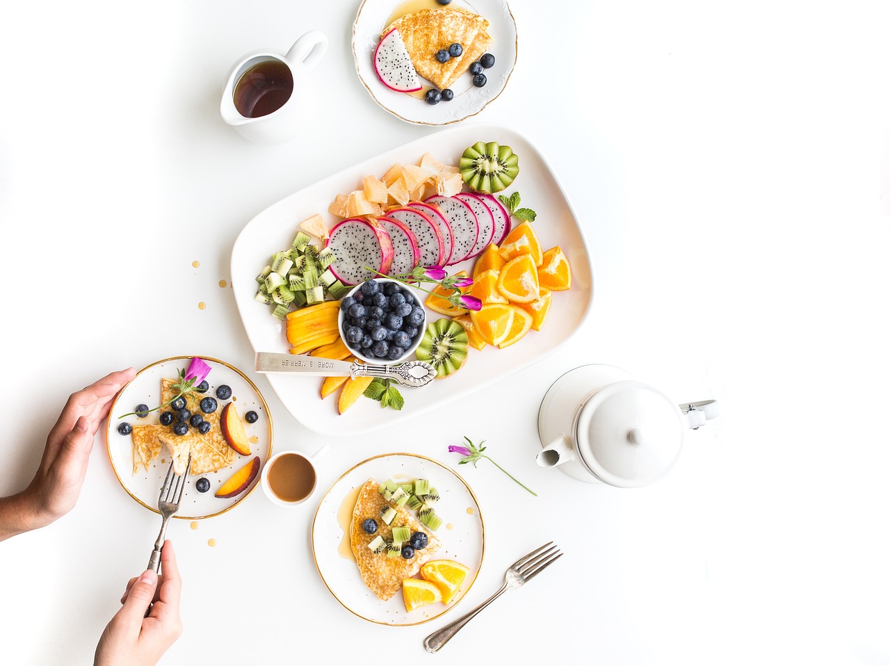 A person presents a colorful plate filled with fresh fruits and vegetables, showcasing healthy eating for wellness.