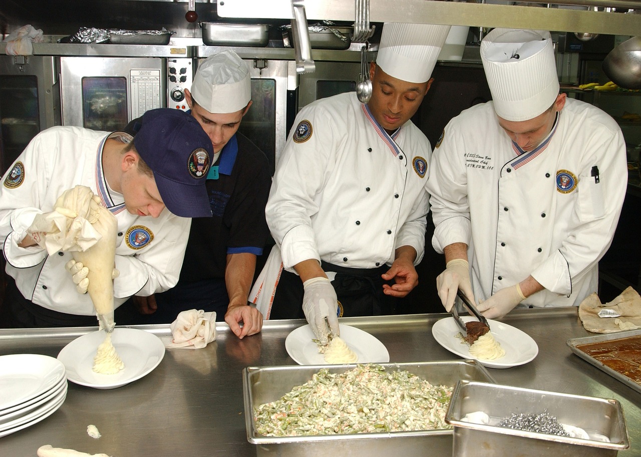 Chefs collaborating in a professional kitchen, expertly preparing food and demonstrating their culinary skills and teamwork.