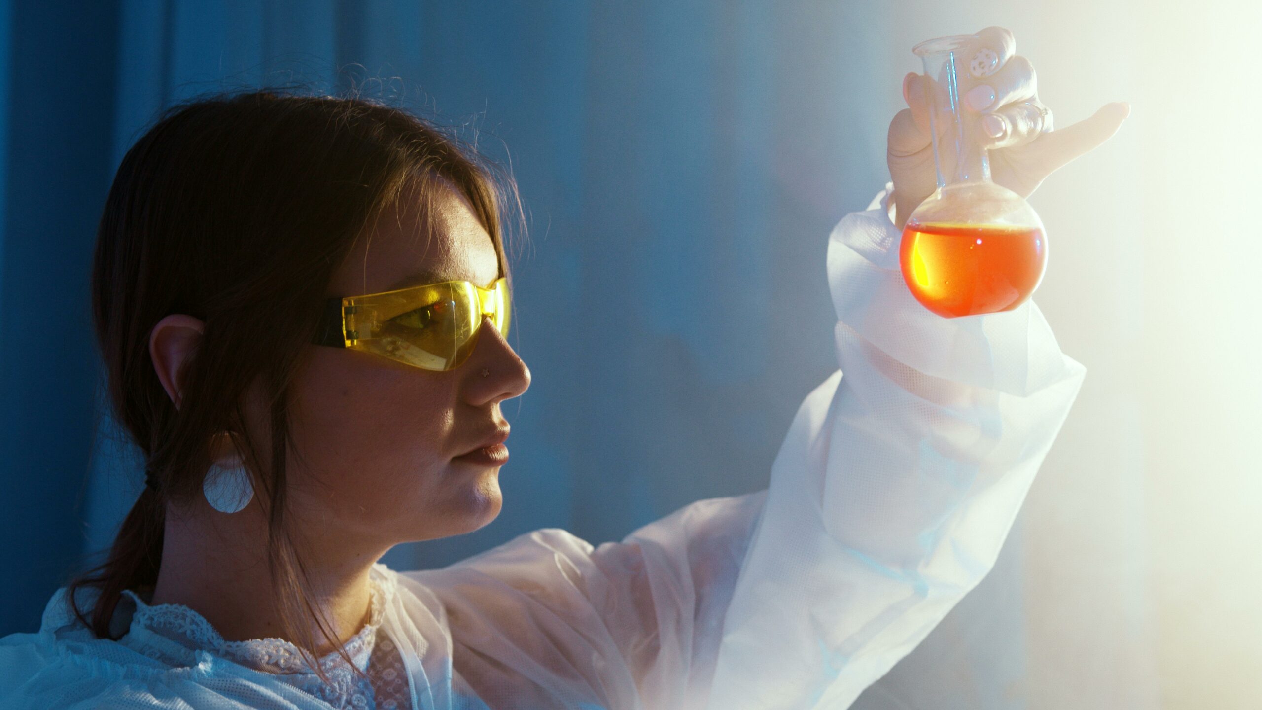 A Clinical Laboratory Technologist in a lab coat proudly holds a glass of liquid, showcasing her expertise in the field.