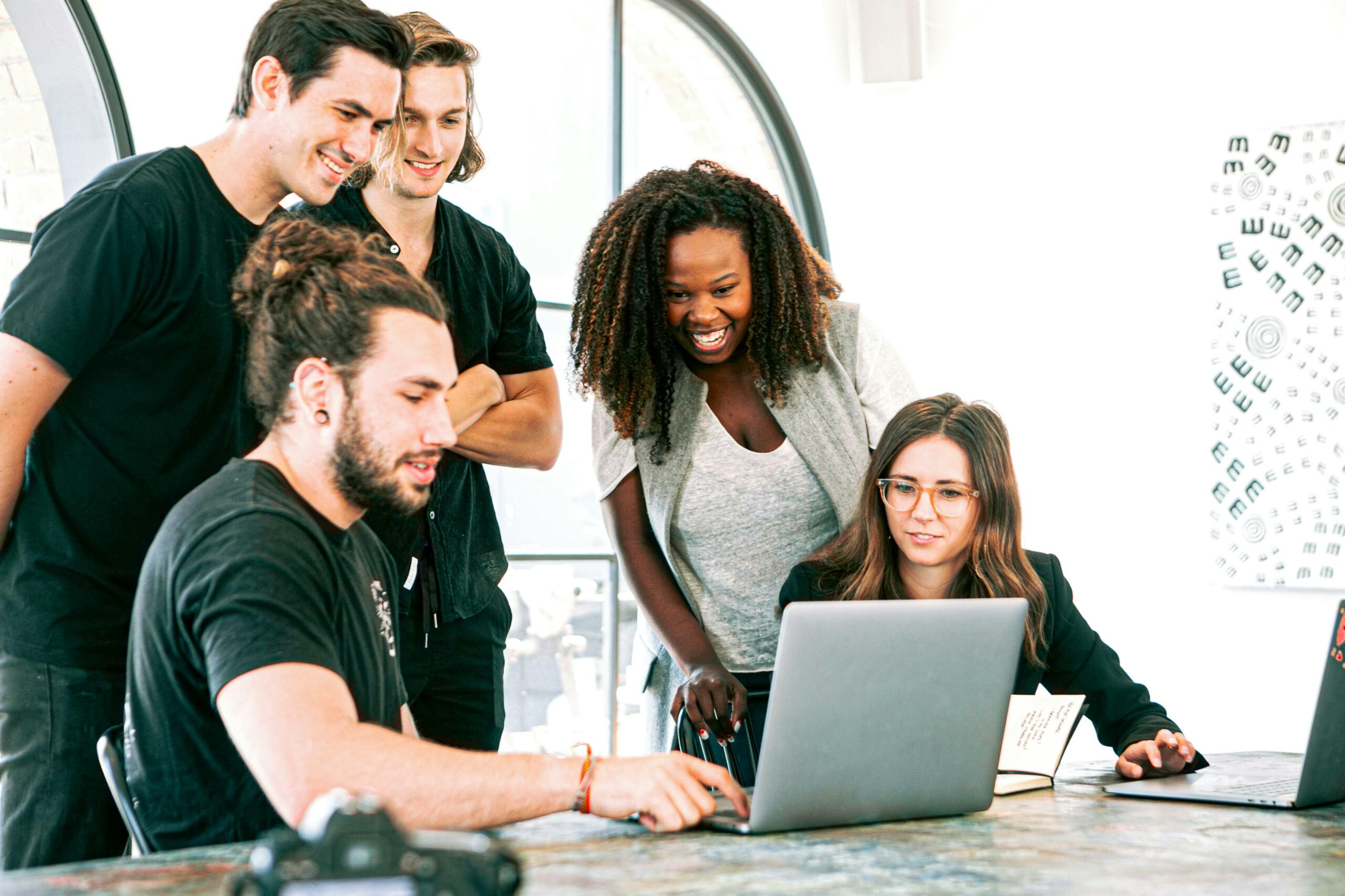 Image featuring a team of professionals gathered around a laptop, engaged in discussion and collaboration at a creative agency.