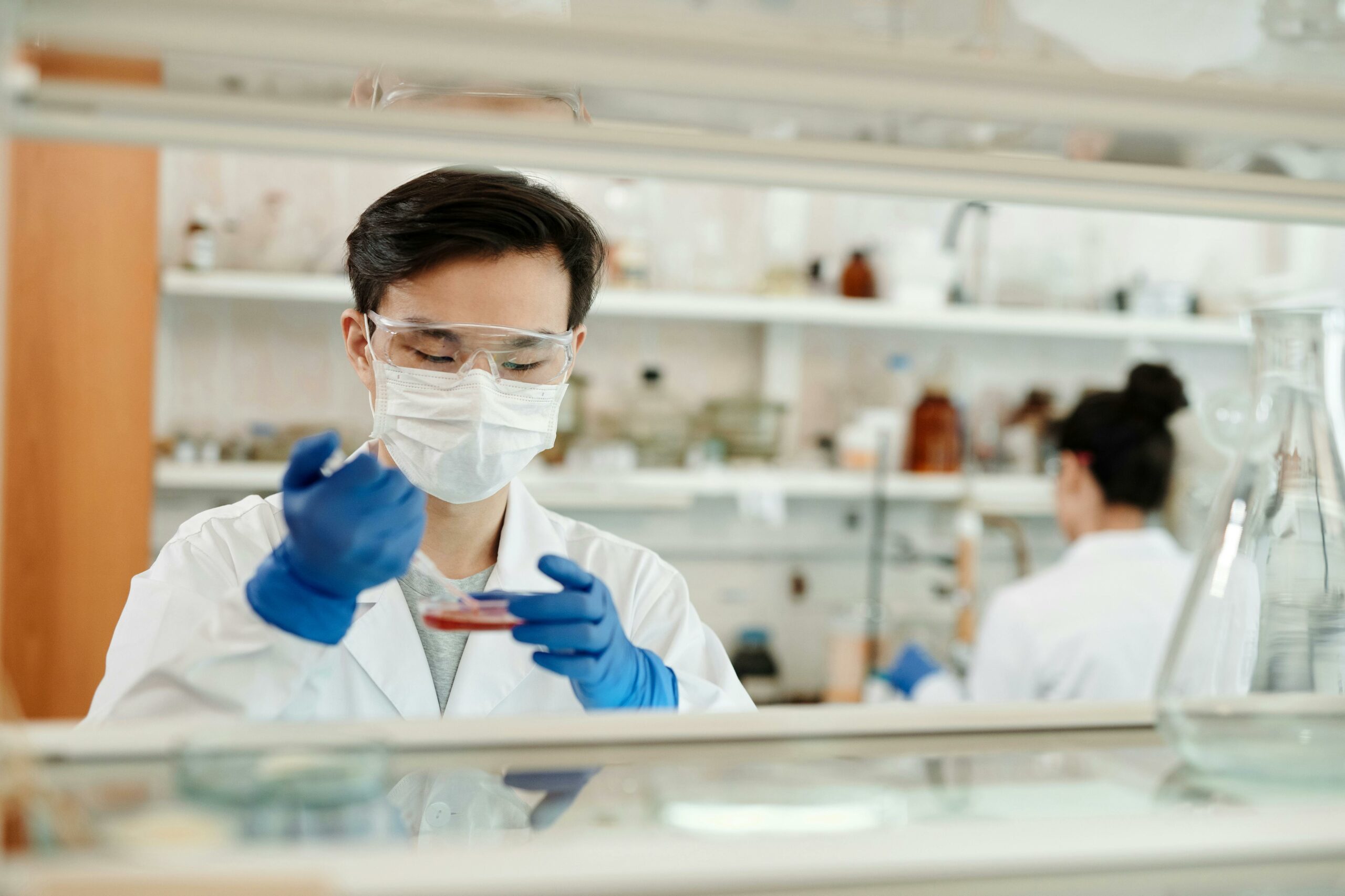 A pharmacy staffing agency owner in a lab coat and gloves holds a test tube, symbolizing scientific expertise and professionalism.