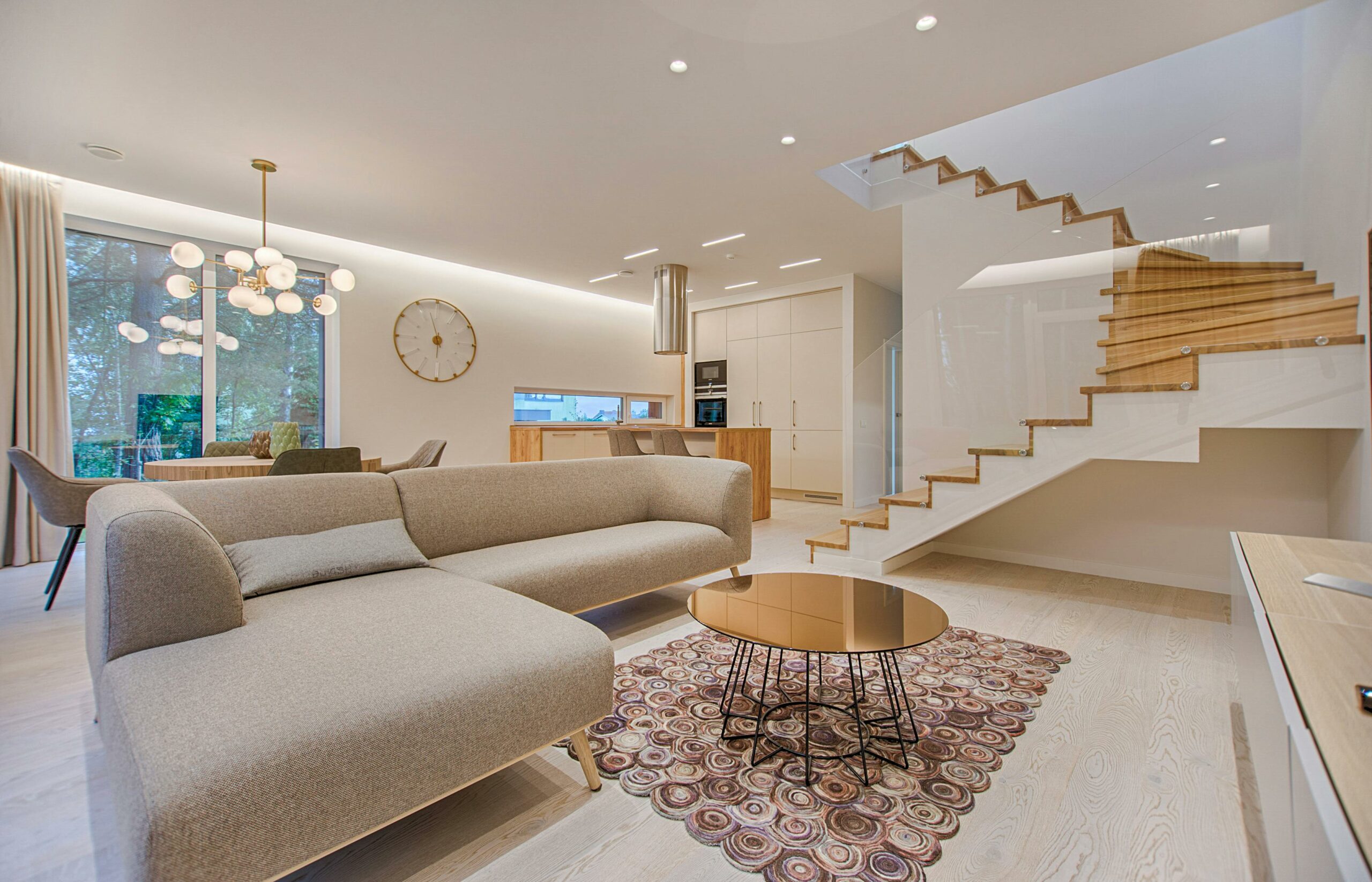 A sleek modern living room with a comfortable couch and a prominent staircase, exemplifying refined interior design services.