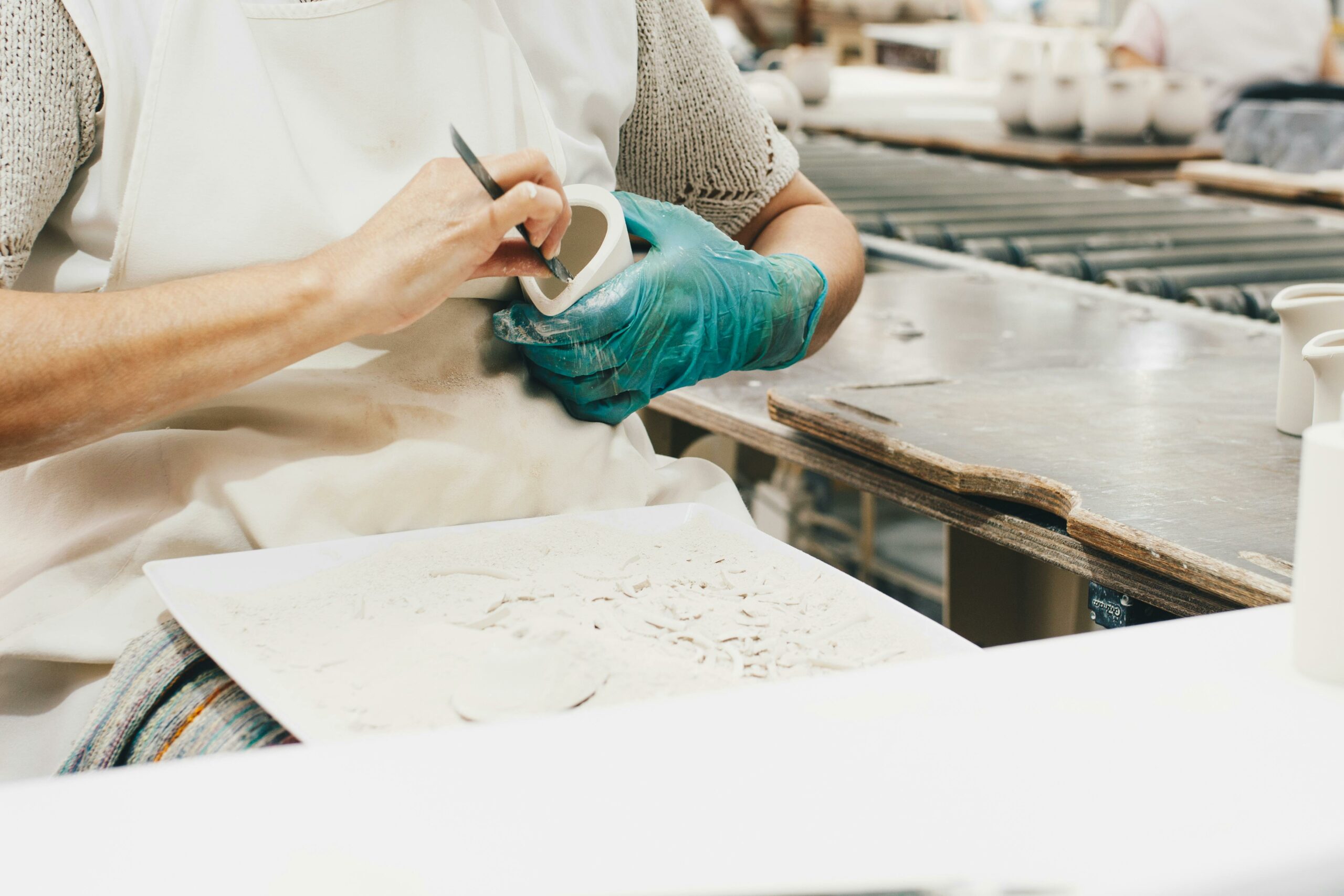 A woman skillfully shapes clay on a pottery wheel in her artisan studio, creating unique handcrafted ceramics for her gallery.