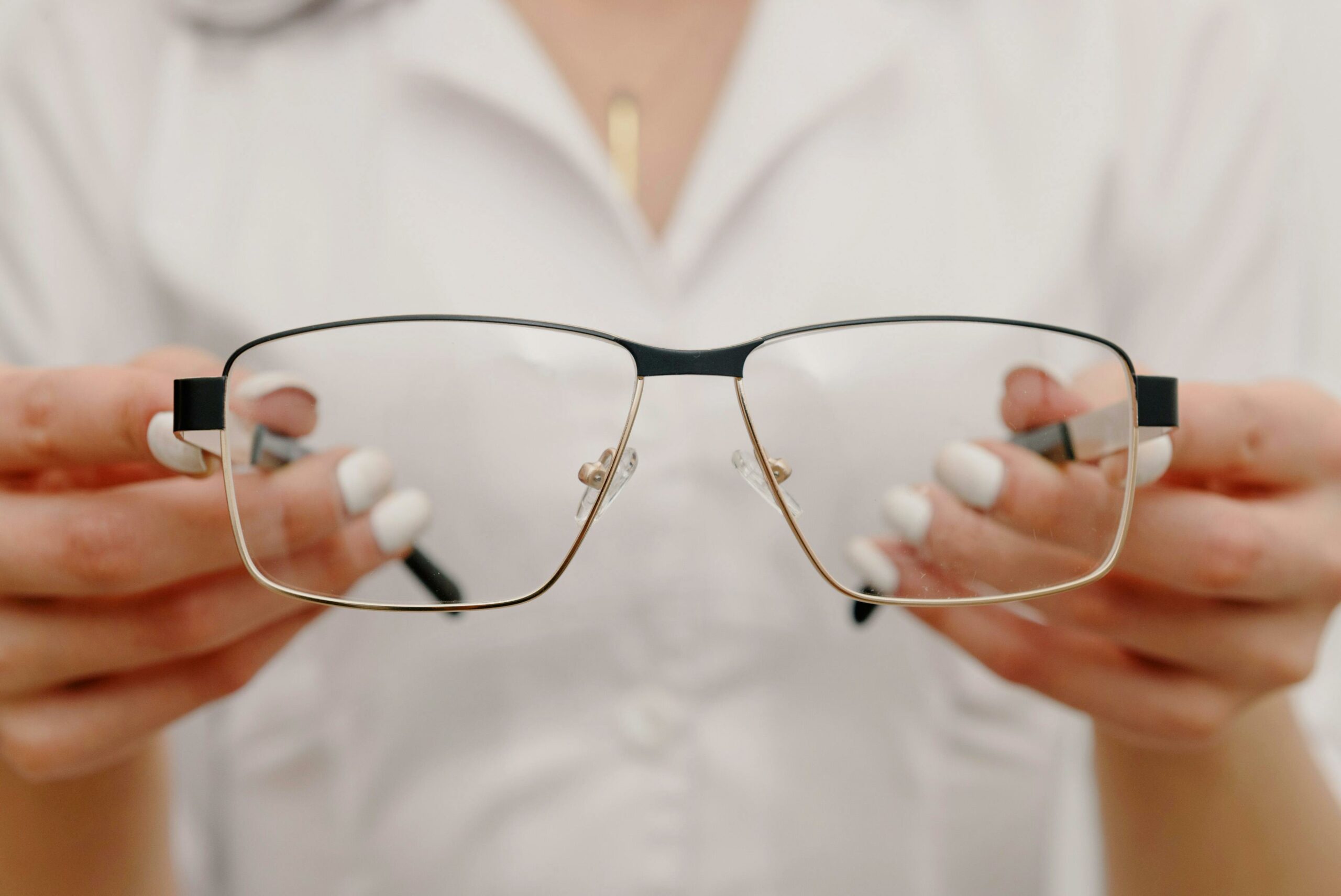 In an optometry setting, a woman displays a pair of glasses, emphasizing her role in helping clients choose eyewear.