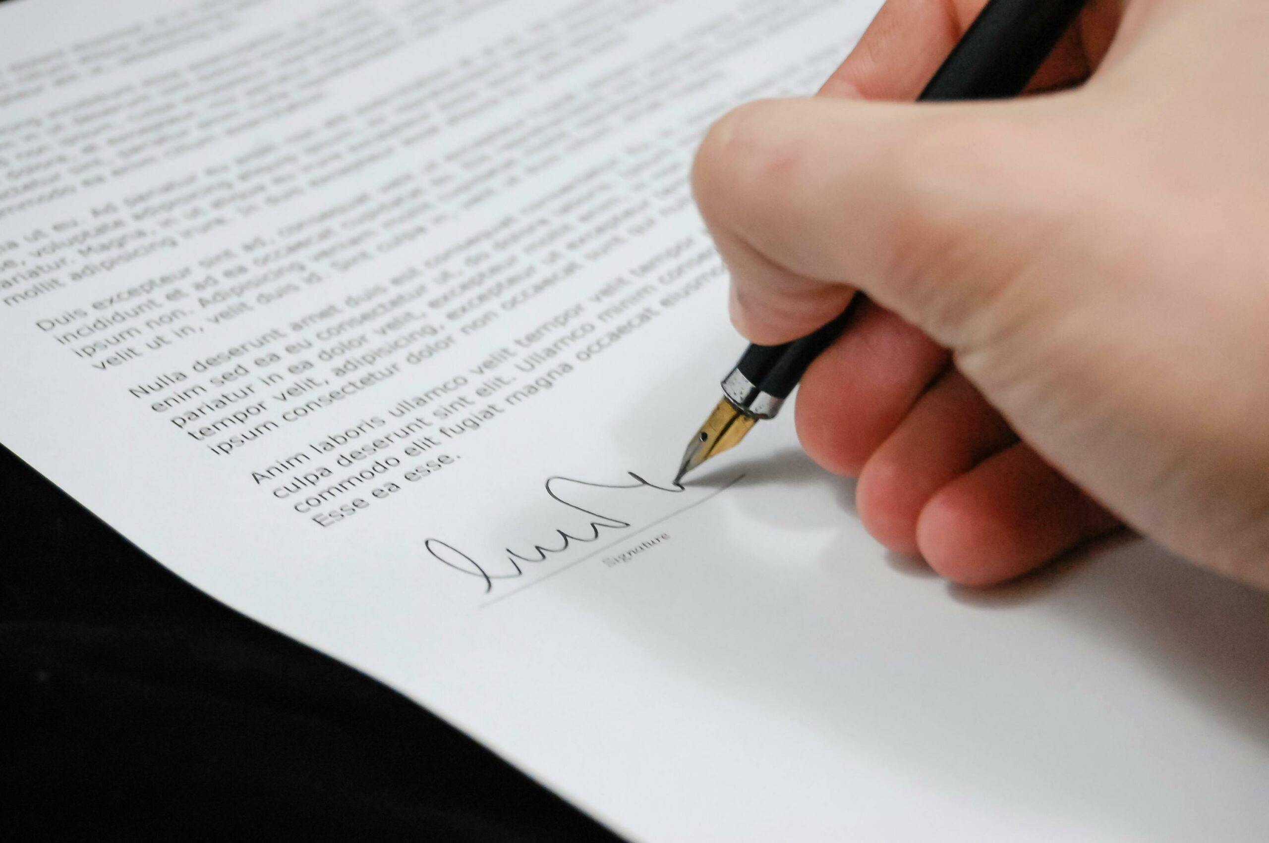 Image featuring a correctional facility management business owner is seen signing a contract with a pen, indicating a formal commitment.