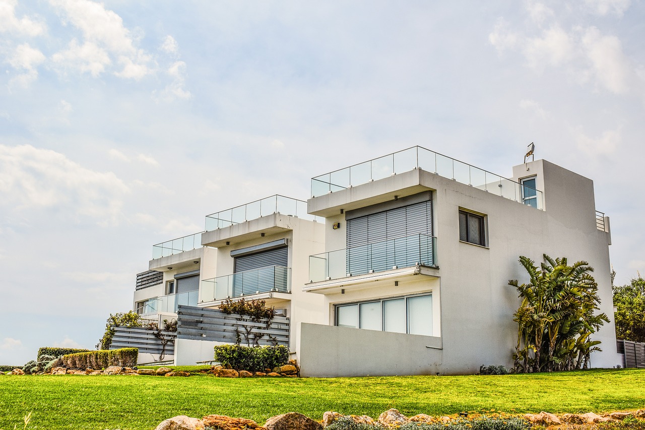 A contemporary house featuring a balcony and a lush grassy area, ideal for real estate appraisal and assessment services.