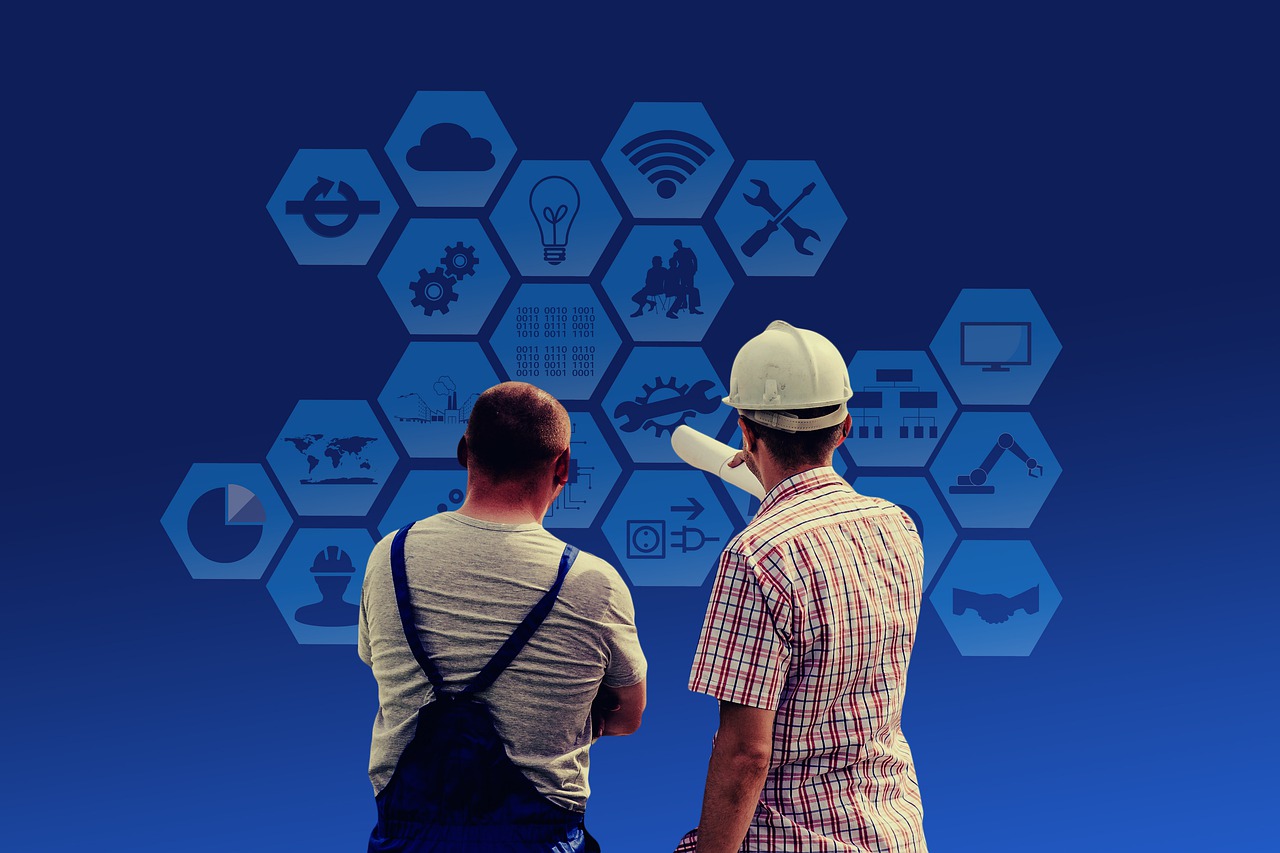 Two men wearing hard hats examine a blue backdrop, symbolizing teamwork in an industrial design firm environment.