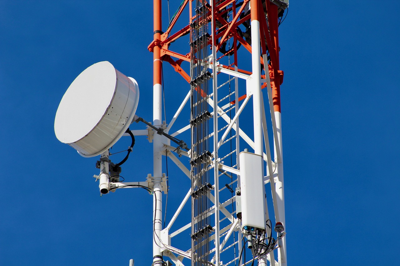 A cellular tower equipped with a satellite dish and antenna, representing a telecommunication installation and repair service.