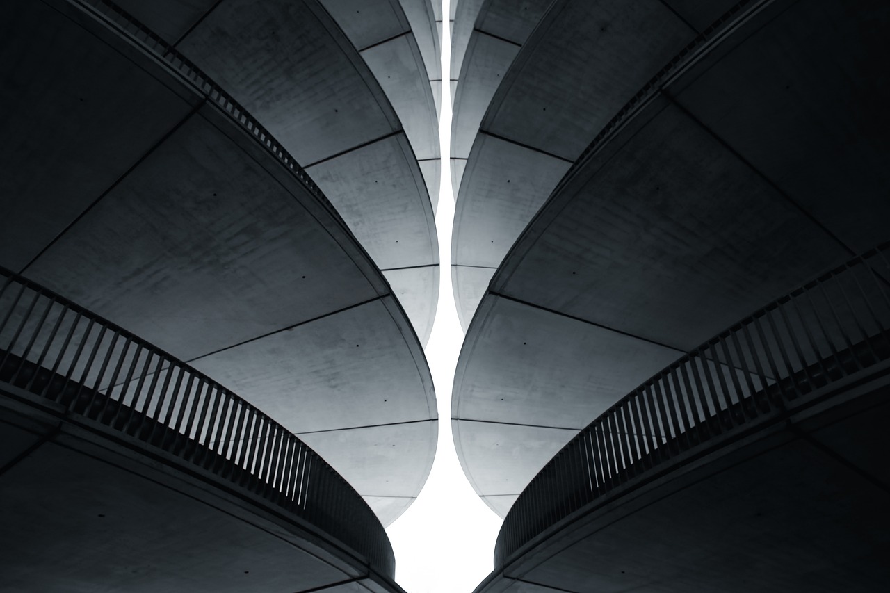 A monochrome photograph of a building, highlighting a striking spiral staircase, symbolizing design and structural integrity.