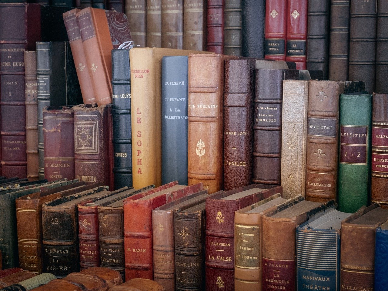 A large stack of old books piled atop one another, symbolizing the rich history of Library Support Services.