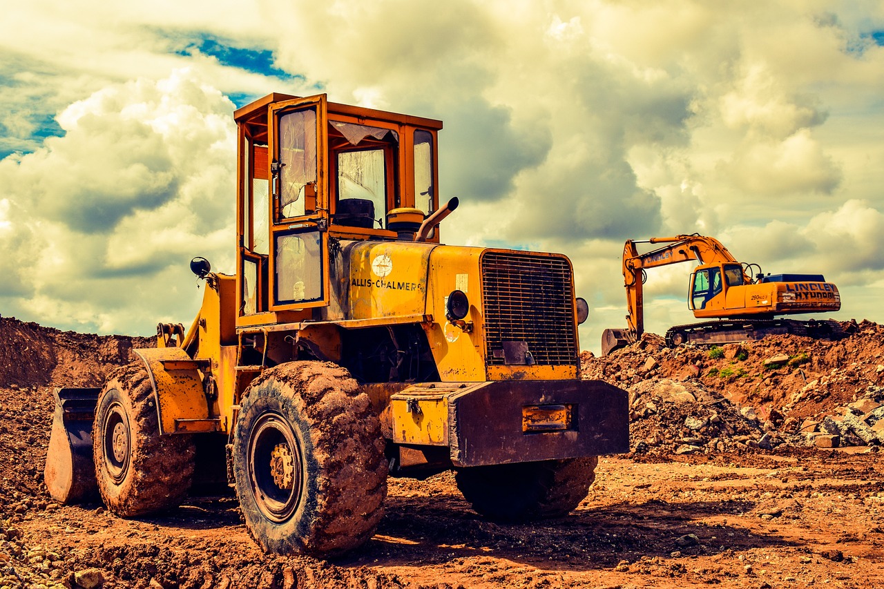 A yellow bulldozer is seen working on a dirt field, representing the heavy vehicle service industry.