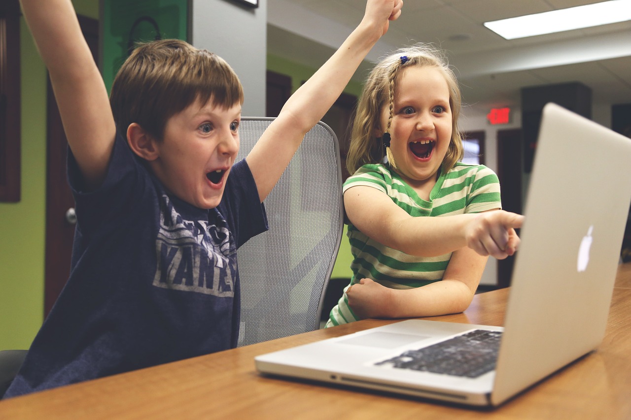 Two children engaged in learning, sitting in front of a laptop, showcasing the importance of technology in education.