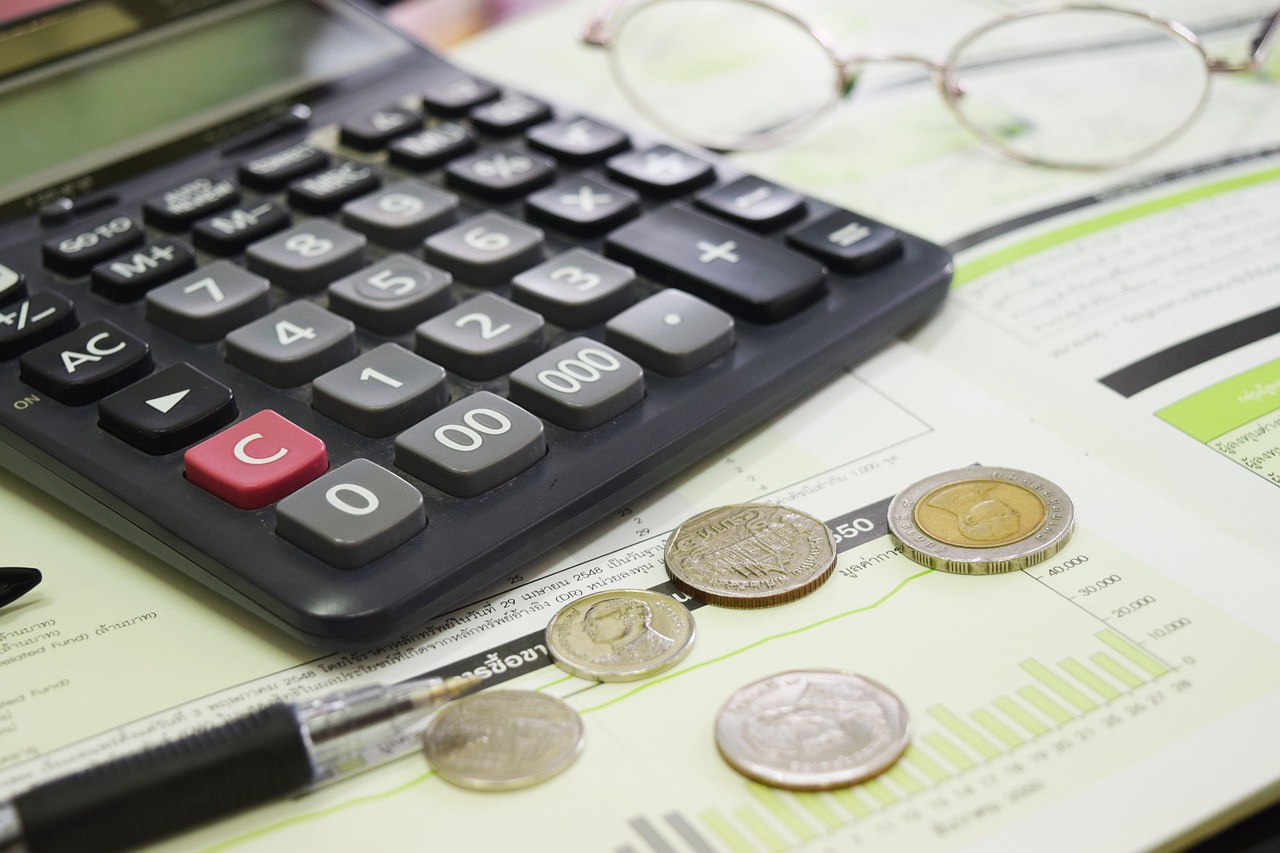 An image featuring a calculator, pen, coins, and glasses on paper, illustrating the analytical work of an economic consulting firm.