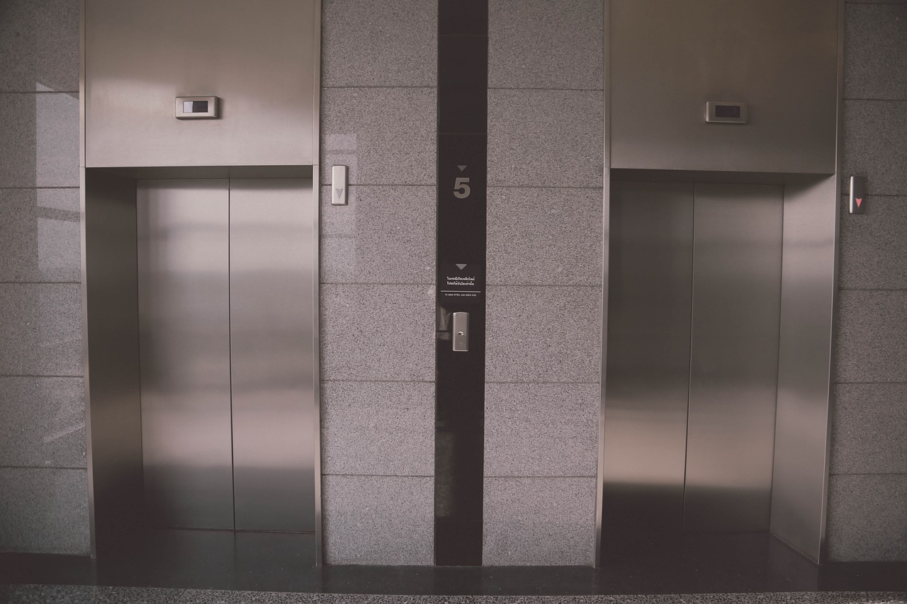 mage of two elevators featuring black doors, representing the expertise in elevator installation and repair.