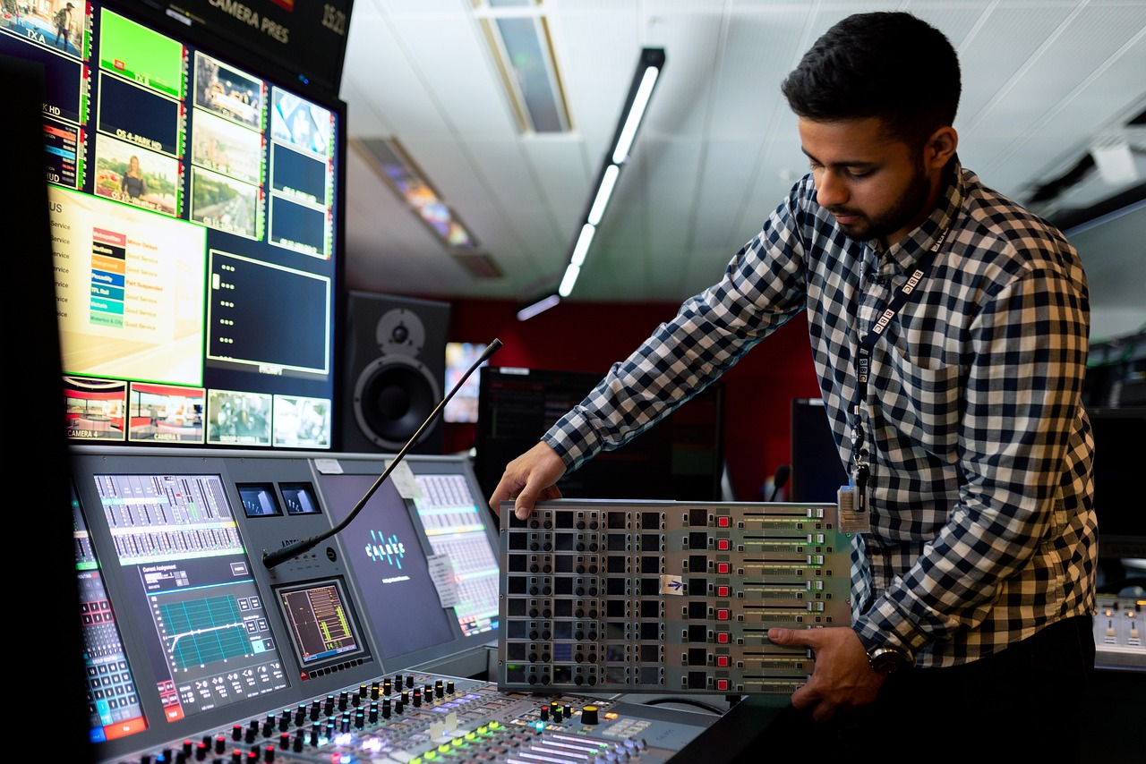 picture of a man operating a mixer in a recording studio, showcasing his expertise as a broadcast and sound engineering business owner.