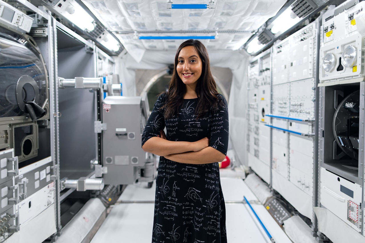 A woman in a space suit stands confidently in a spacious room, embodying innovation as a Technical Sales Engineering Firm Owner.