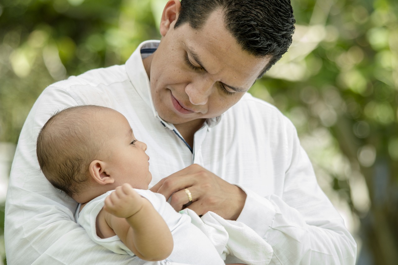 Image featuring a child care center owner gently holds a baby in his arms, showcasing a nurturing and caring environment.