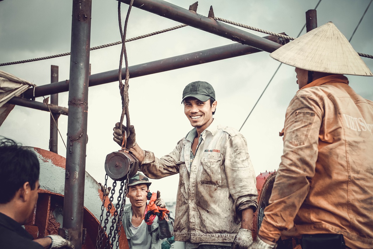 Two construction workers wearing construction hats engage in a discussion, representing the construction labor industry.