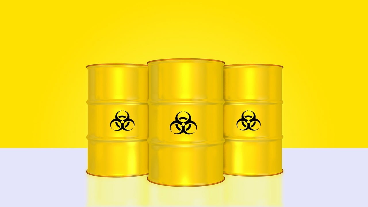 Three yellow barrels marked with biohazard symbols, indicating hazardous materials for removal services.