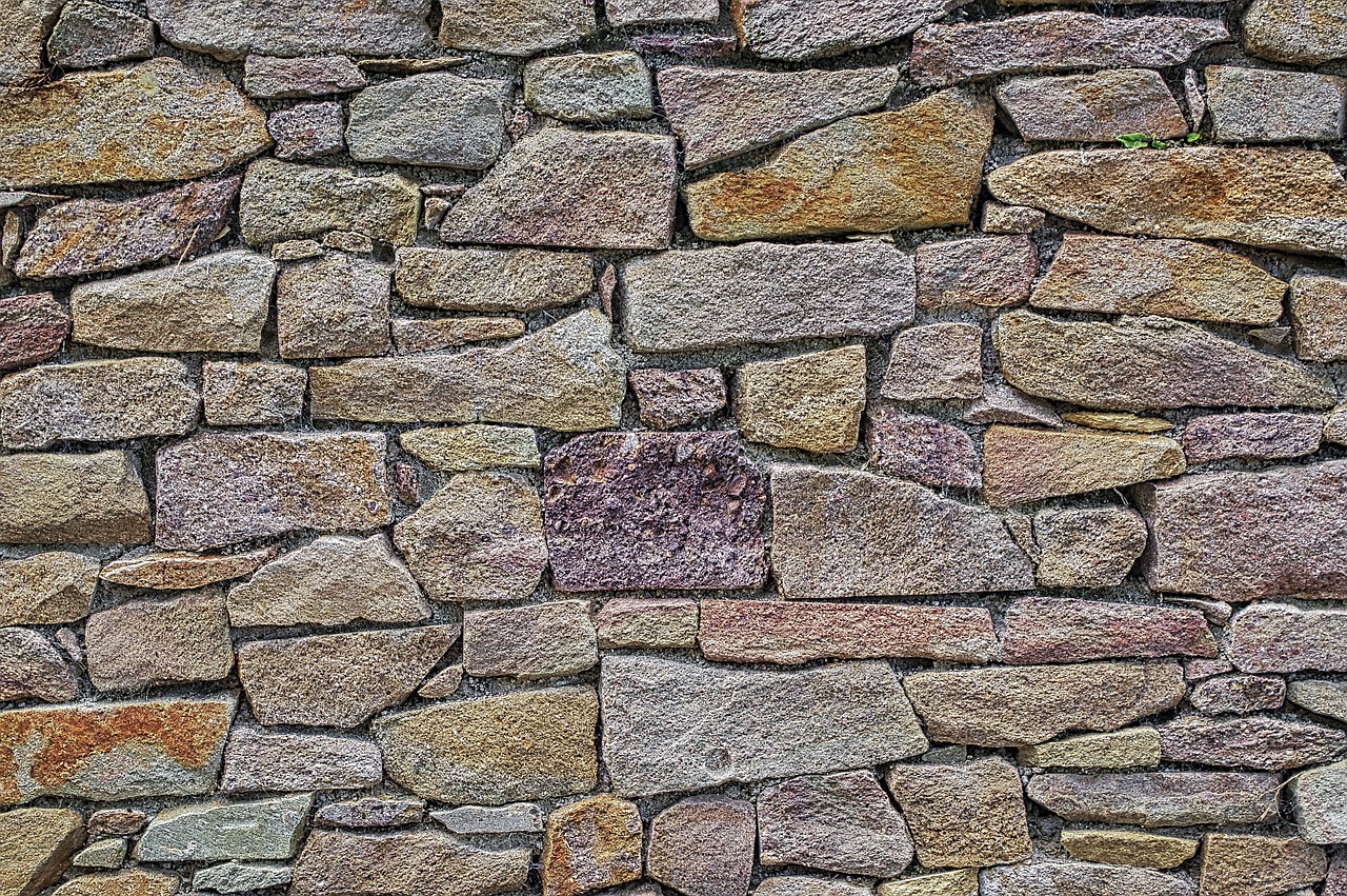 A stone wall showcasing a variety of colorful stones, highlighting the craftsmanship of a masonry business owner.