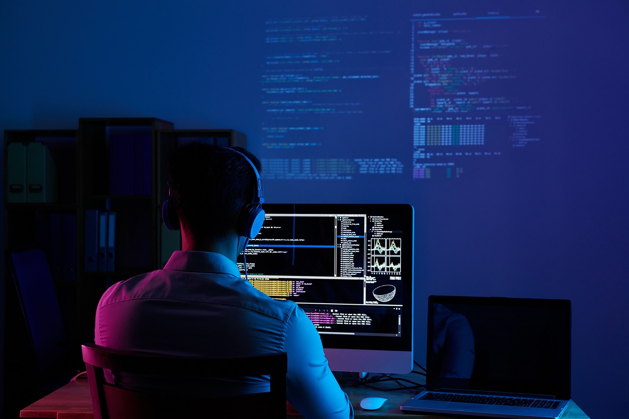 image featuring a man, owner of a computer science consultancy, seated at a desk, concentrating on his work at a computer monitor.