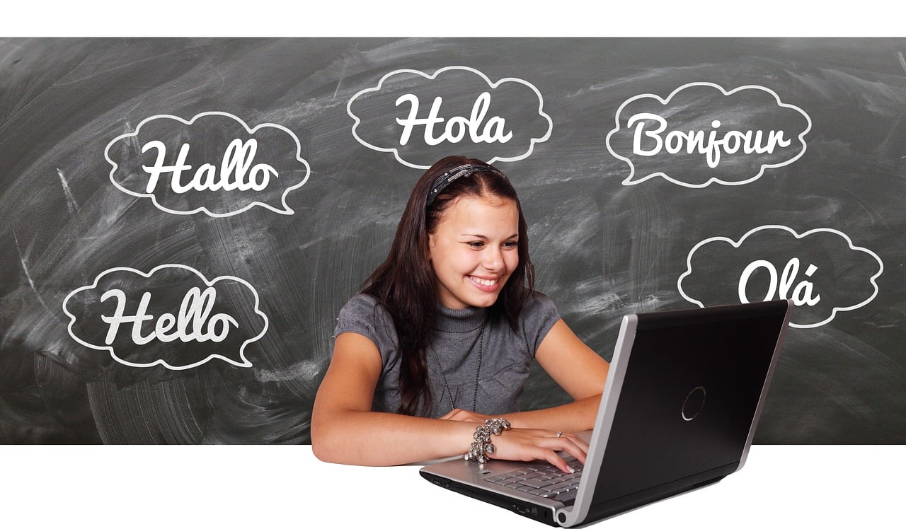 A woman in front of a laptop shows the word "hello" in multiple languages, representing language interpretation and translation services.