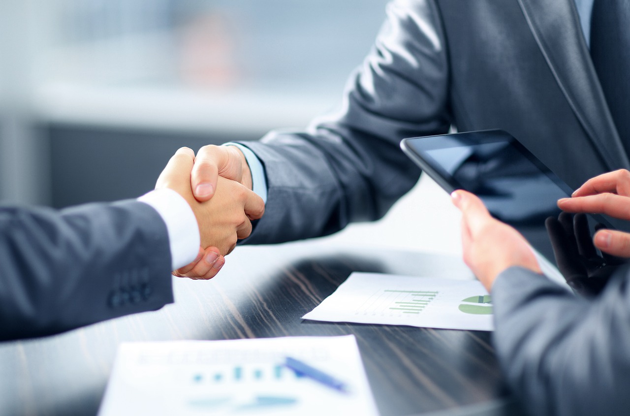 Two business professionals shaking hands over a table, symbolizing a successful partnership in a cashier business.